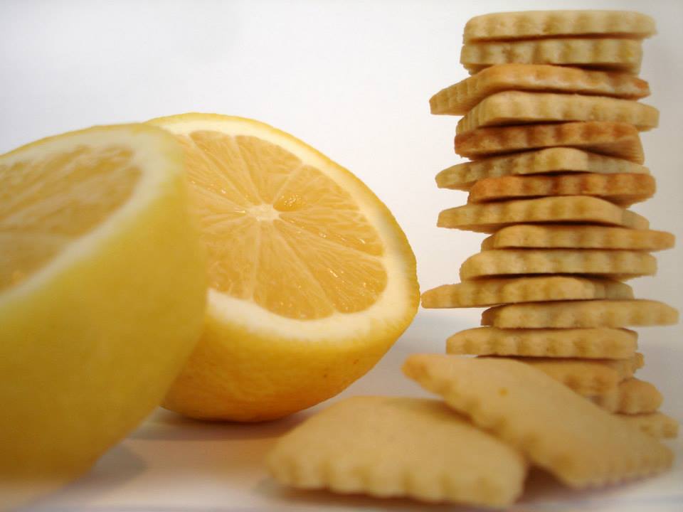 Limão cortado ao meio ao lado de bolachas empilhadas sobre fundo branco