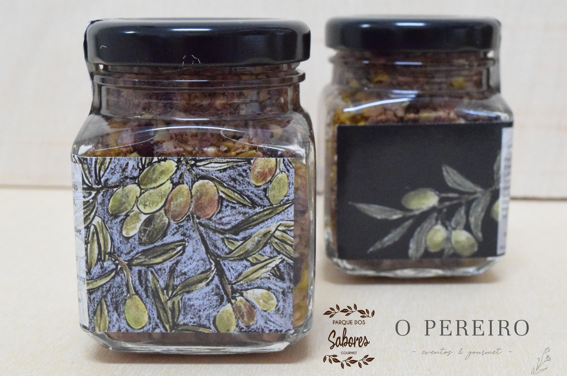Dois frascos de vidro com tampa preta e rótulos com ilustrações de ramos de oliveira e azeitonas
