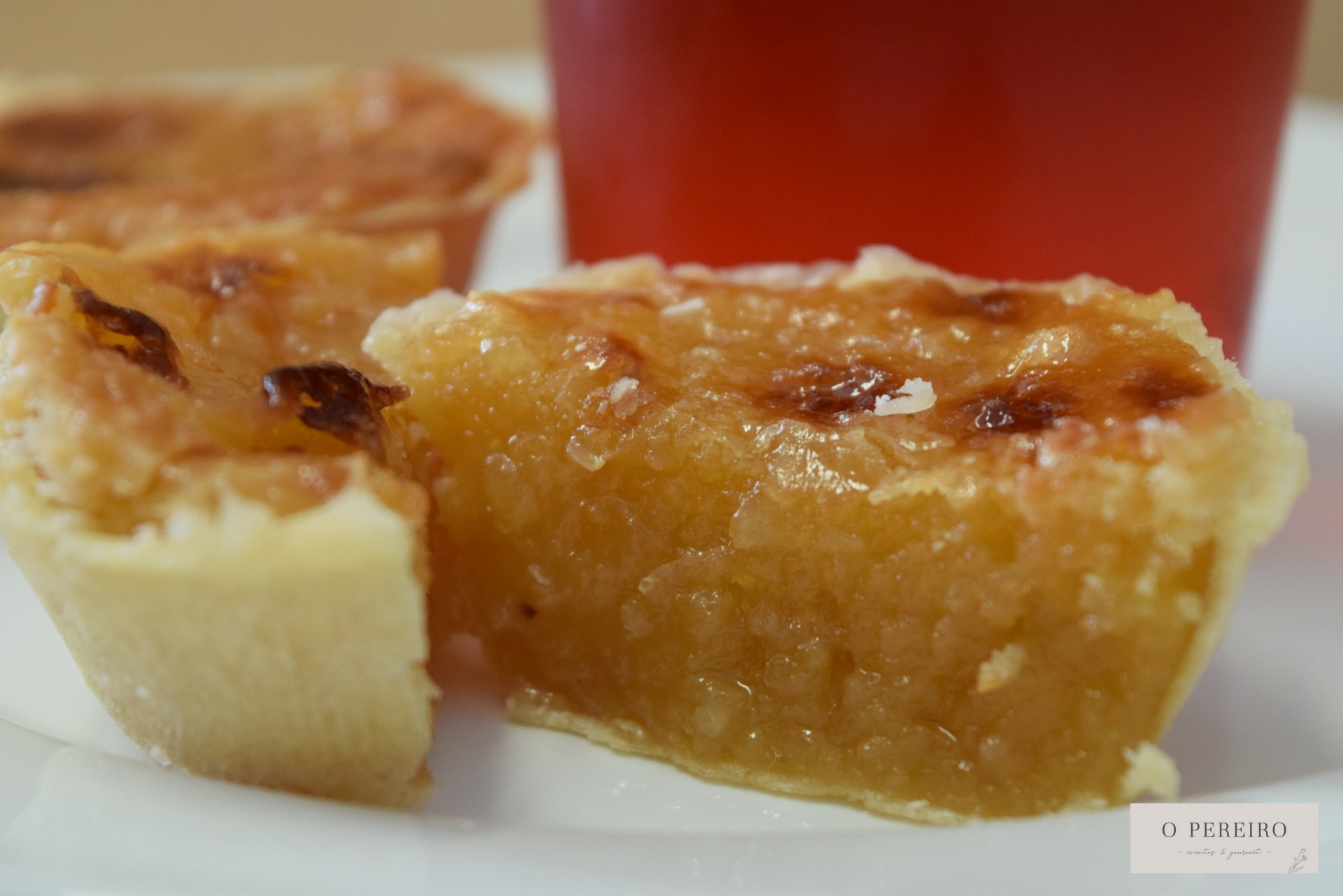 Tarte de massa folhada cortada ao meio com copo vermelho ao fundo