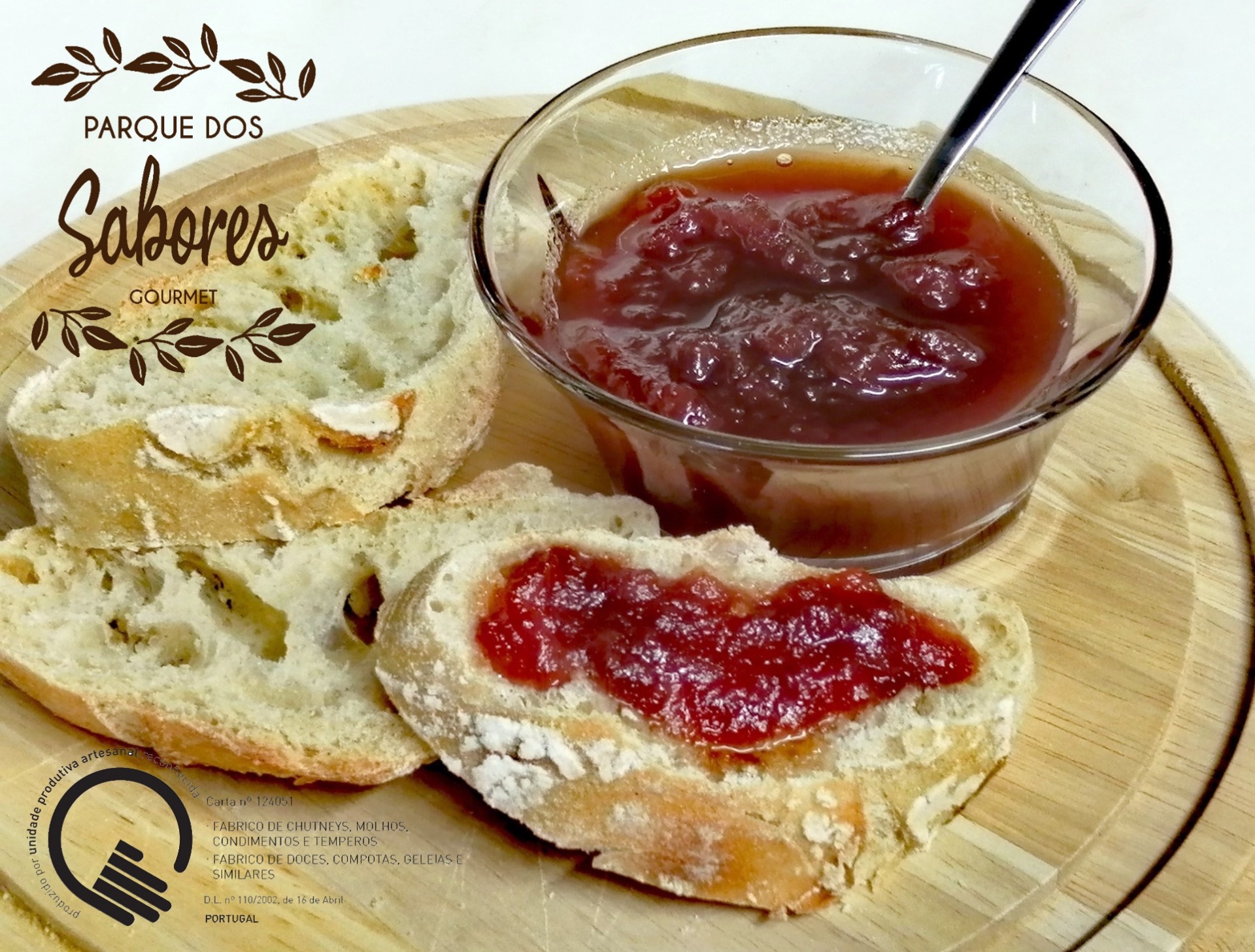 Doce (Compota) de Tomate Pão rústico com geléia vermelha em tábua de madeira e taça de vidro.