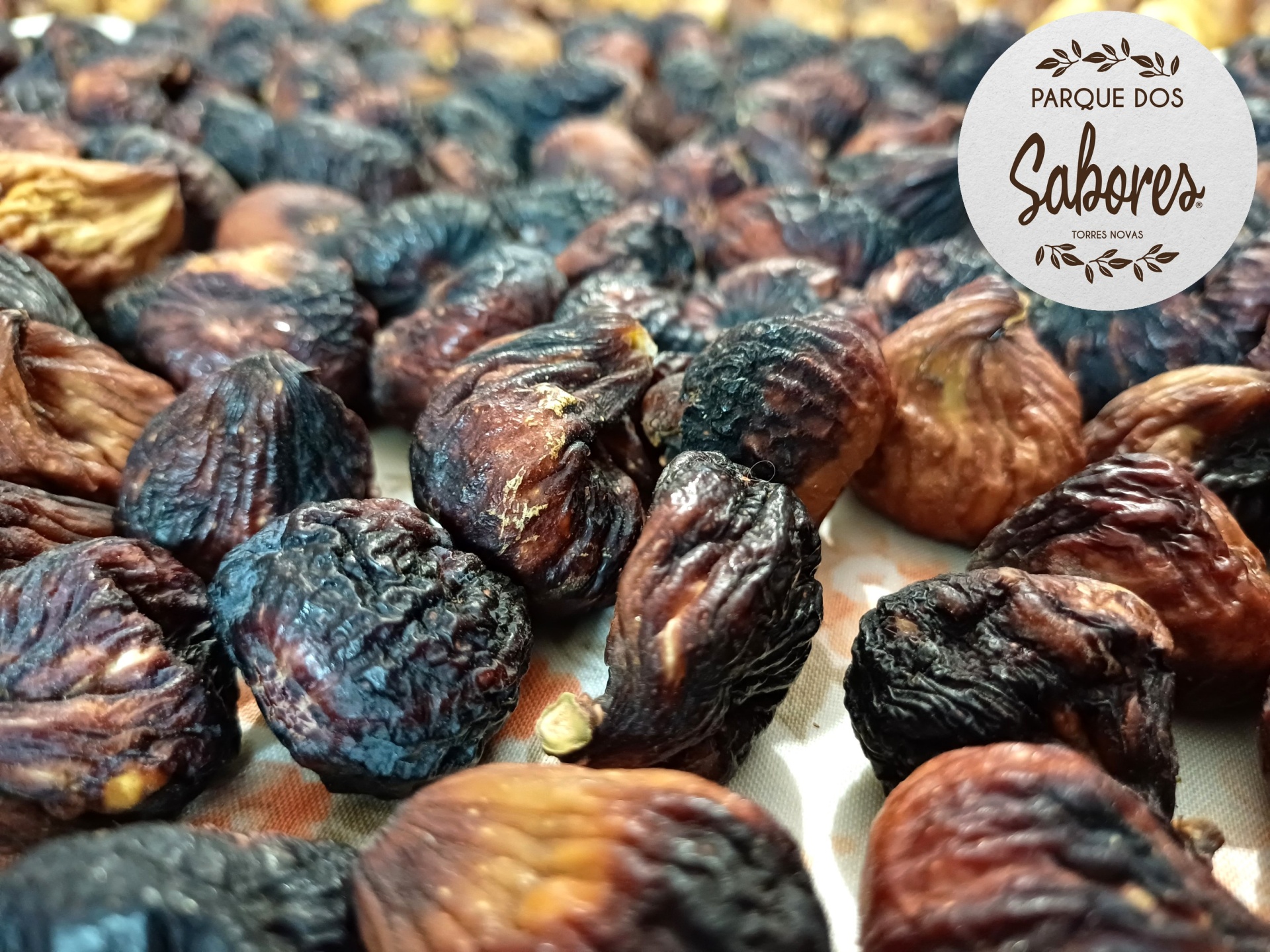 Figos secos enrugados em tons castanhos e pretos com logótipo Parque dos Sabores