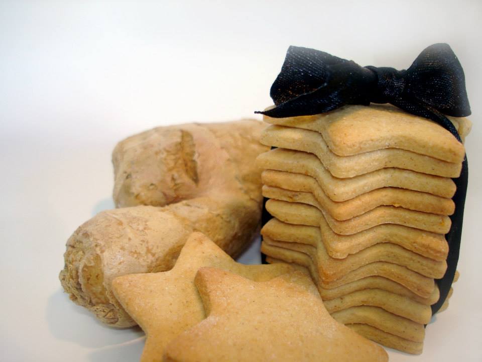 Biscoitos em forma de estrela e empilhados com fita preta ao lado de biscoitos em forma de arco