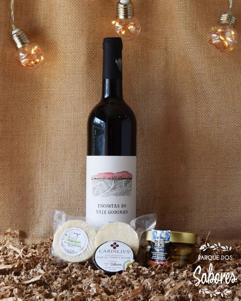 Garrafa de vinho e produtos artesanais sobre papel kraft com fundo de juta e luzes penduradas