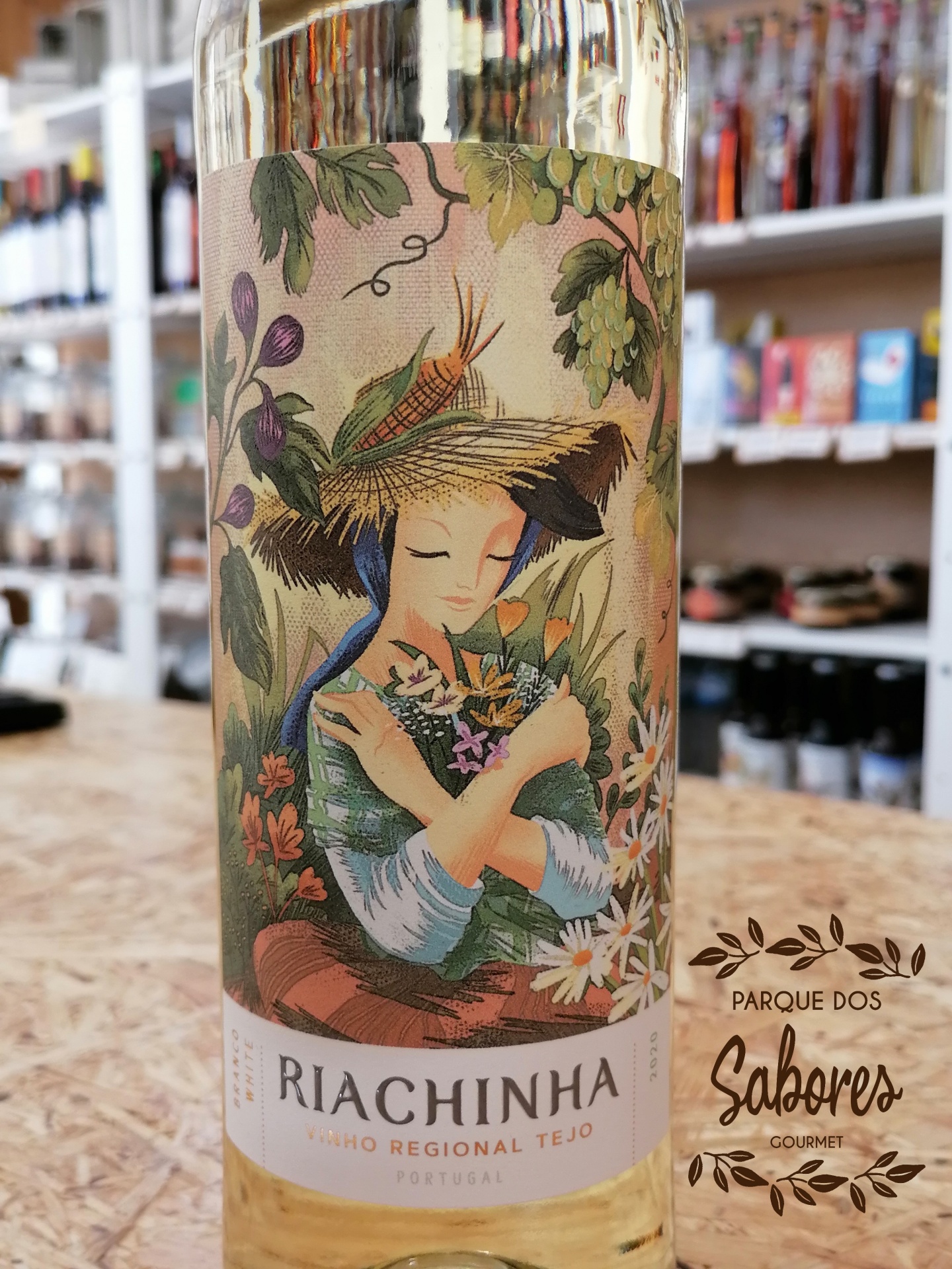 Garrafa de vinho branco com rótulo ilustrado de mulher com chapéu de palha e flores