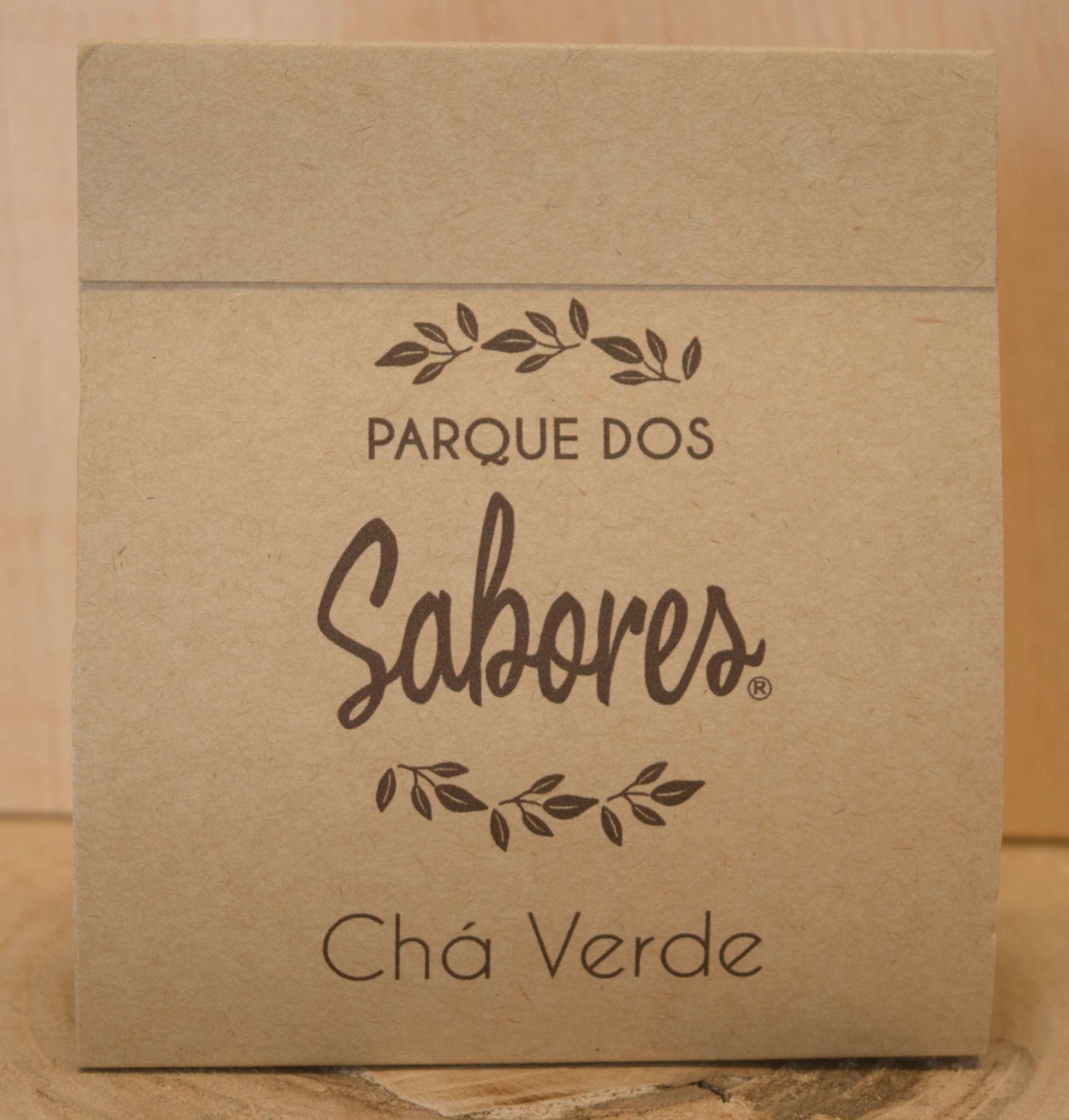 Embalagem de chá verde Parque dos Sabores em papel castanho com texto em castanho e decoração de ramos com folhas.