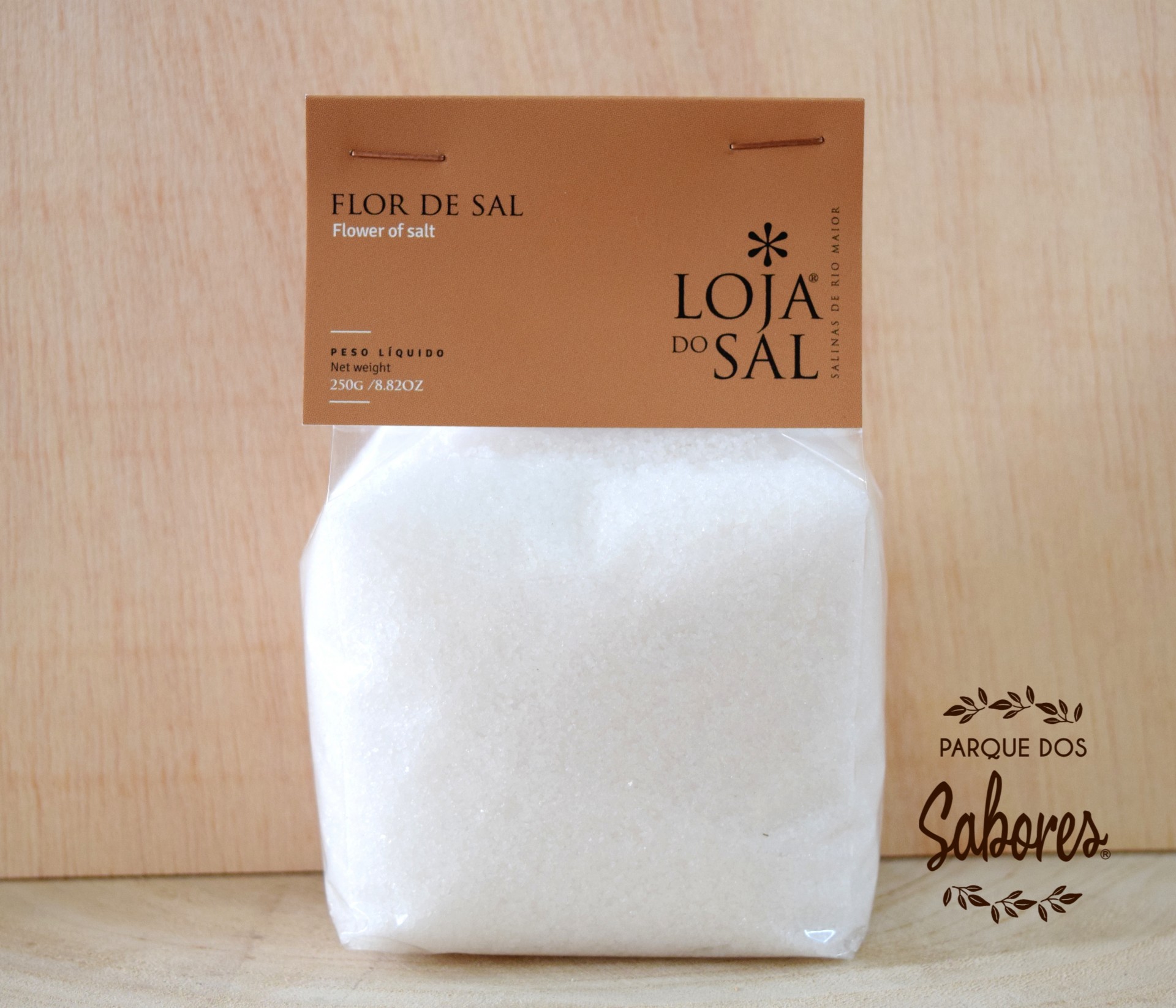 Frasco de flor de sal Fonte Salina "Loja do Sal" Pacote de Flor de Sal Loja do Sal com 250g sobre superfície de madeira clara
