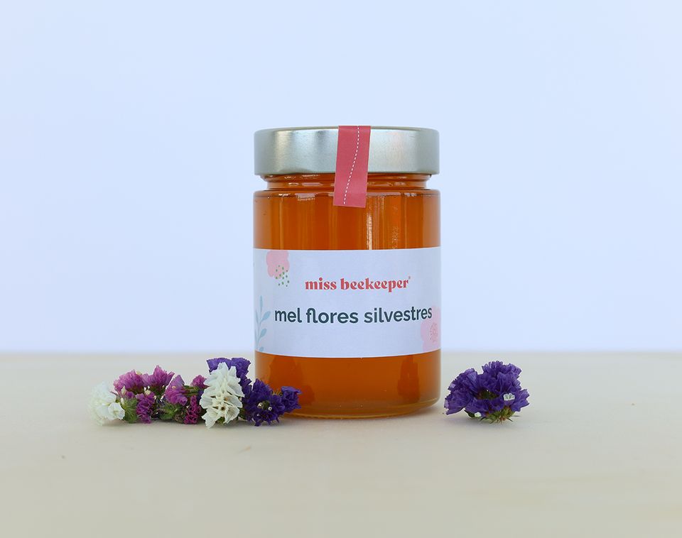 Frasco de mel de flores silvestres da miss beekeeper com flores ao redor