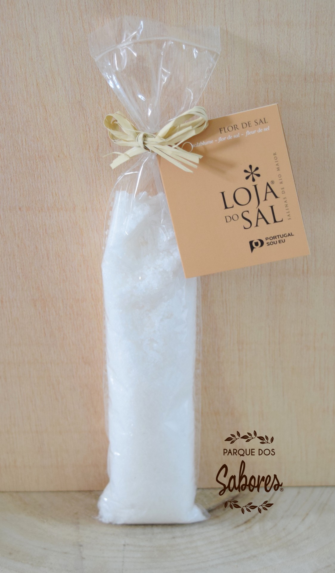 Frasco de flor de sal Fonte Salina "Loja do Sal" Pacote transparente com sal grosso e etiqueta amarela, sobre madeira clara