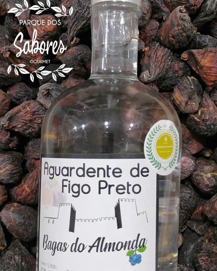 Frasco de aguardente de figo preto Bagas do Almonda com fundo de figos pretos secos