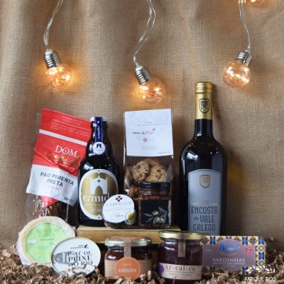 Conjunto de produtos gourmet com pão, cerveja, bolachas, mel, vinho, queijo, patê, doce e sardinhas sobre fundo de juta com luzes
