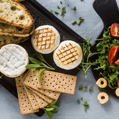 Queijos grelhados, pão, bolachas e salada em tabuleiro