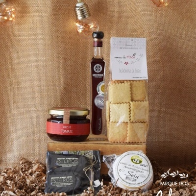 Produtos alimentares compostos por doce de tomate, licor, massa e queijos sobre fundo castanho com luzes decorativas