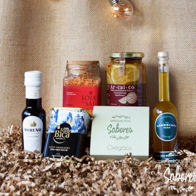 Produtos gourmet com azeite, sal temperado, pimentos com limão e orégãos em embalagem decorativa