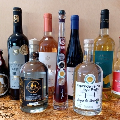 Nove garrafas de bebidas alcoólicas variadas sobre superfície de madeira