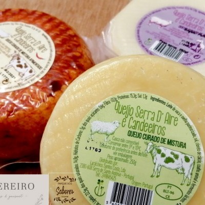 Três queijos curados de mistura com etiquetas coloridas sobre uma superfície de madeira