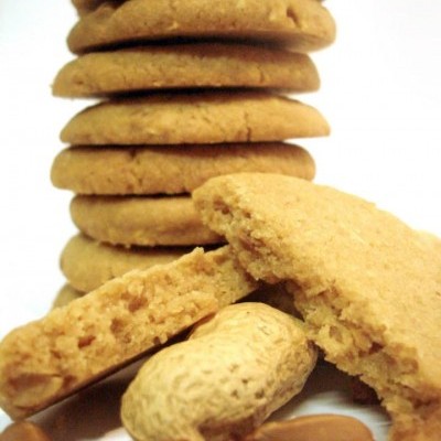 Bolachas douradas empilhadas com amendoins em fundo branco