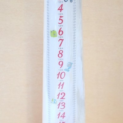 Vela branca alta com números vermelhos e desenhos coloridos em fundo de madeira clara.