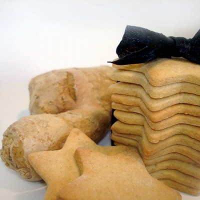 Biscoitos em forma de estrela e empilhados com fita preta ao lado de biscoitos em forma de arco