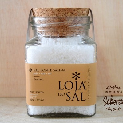Frasco de vidro com sal grosso e tampa de cortiça, com rótulo bege e texto visível.