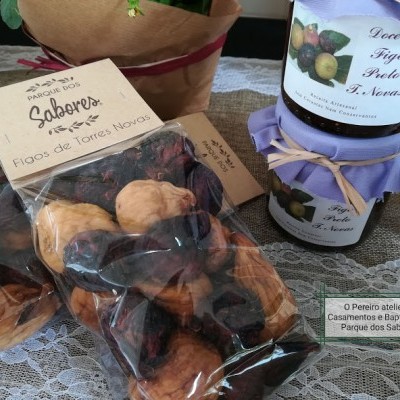 Pacote de figos secos e frascos de compota de figo preto com tampa coberta por tecido lilás sobre toalha rendada