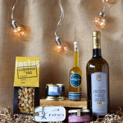 Produtos gourmet sobre aparas de madeira com vinho branco e luzes decorativas