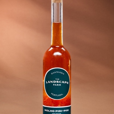 Garrafa de vidro com molho piri-piri e tampa de cortiça sobre fundo castanho