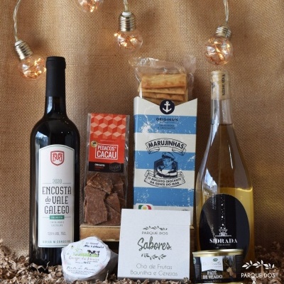 Produtos gourmet com vinho, bolachas, chocolate e chá em fundo de juta com luzes decorativas