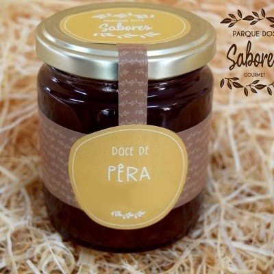 Frasco de doce de pêra com rótulo amarelo e tampa dourada sobre palha