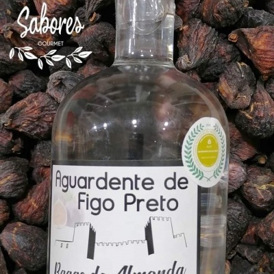 Frasco de aguardente de figo preto Bagas do Almonda com fundo de figos pretos secos