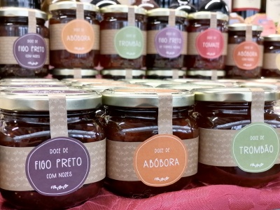 Frascos de vidro com doces variados com rótulos coloridos em cima de tecido vermelho