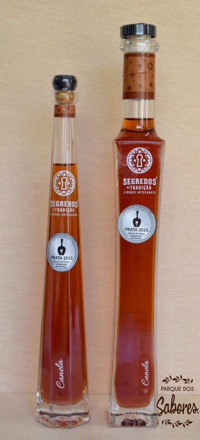 Duas garrafas altas de licor cor âmbar com rótulos brancos e tampa preta
