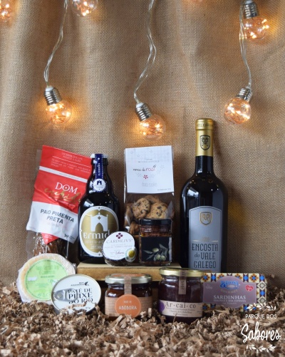 Conjunto de produtos gourmet com pão, cerveja, bolachas, mel, vinho, queijo, patê, doce e sardinhas sobre fundo de juta com luzes