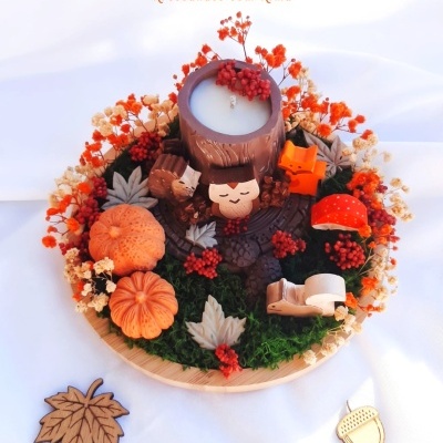 Arranjo decorativo com vela e figuras de madeira em fundo branco