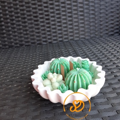 Vaso branco com cactos decorativos verdes sobre superfície trançada castanha