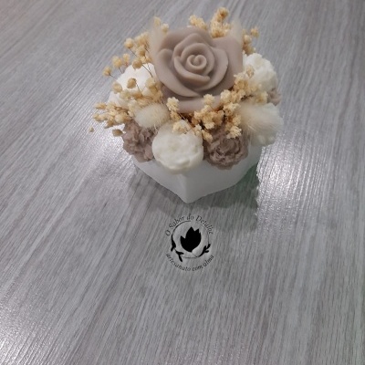 Arranjo decorativo com flores artificiais em vaso branco sobre madeira cinza