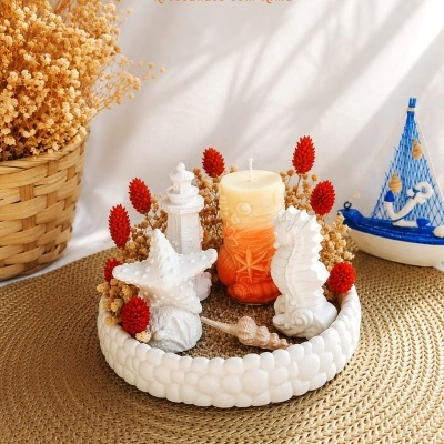 Arranjo decorativo com vela e figuras marinhas em base branca