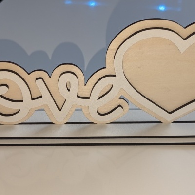 Objeto decorativo de madeira com a palavra love e um coração