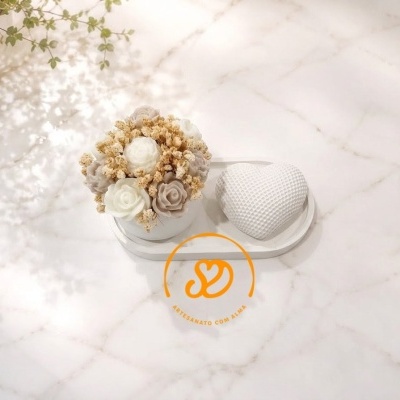 Arranjo decorativo com flores artificiais brancas e bege e coração branco texturizado sobre base branca em superfície marmoreada