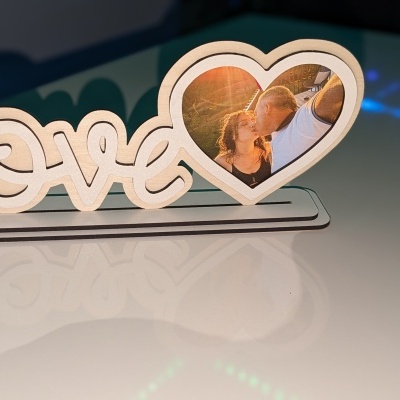 Objeto decorativo de madeira com palavra love e fotografia em forma de coração