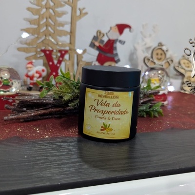 Vela da Prosperidade Canela & Ouro em frasco preto com decoração de Natal ao fundo