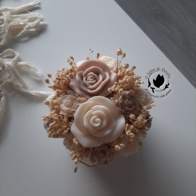 Arranjo floral artesanal com rosas de cera e flores secas sobre superfície branca