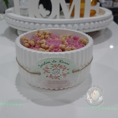 Vela artesanal decorativa em recipiente branco com flores secas e etiqueta Jardim de Rosas