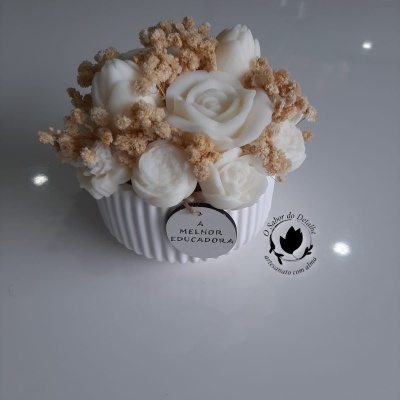 Arranjo decorativo com flores brancas artificiais e ramos secos em base branca com etiqueta