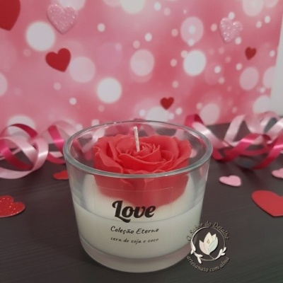 Vela decorativa com flor vermelha em cera dentro de vidro e decoração de corações e fitas
