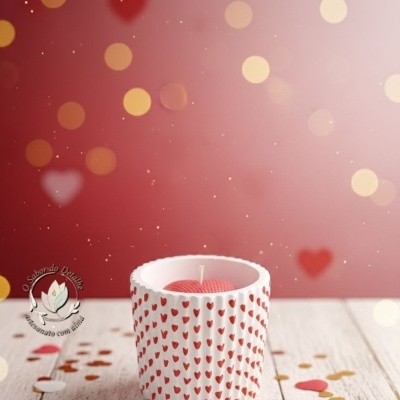 Vela em suporte branco com corações vermelhos e confetes de coração sobre mesa de madeira clara