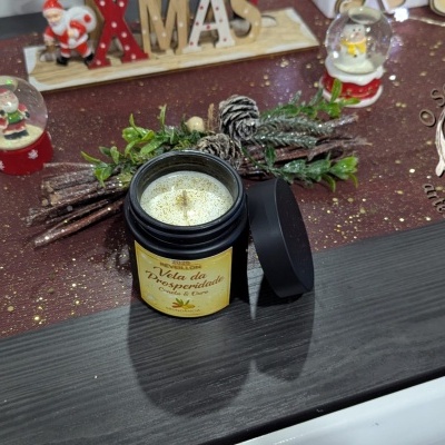 Vela da Prosperidade em frasco preto com glitter dourado e decoração natalícia ao redor