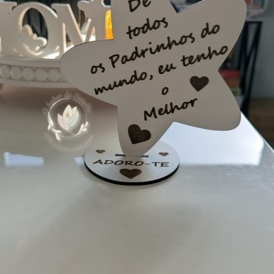 Suporte decorativo em forma de estrela com texto para padrinhos sobre mesa branca