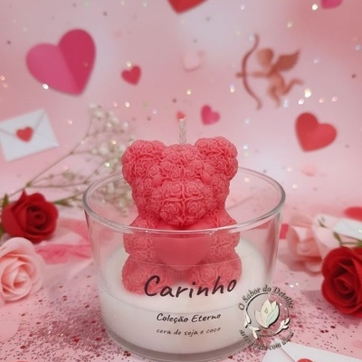 Vela com urso cor-de-rosa de rosas em copo transparente com texto carinhoso num fundo rosa com corações e flores.