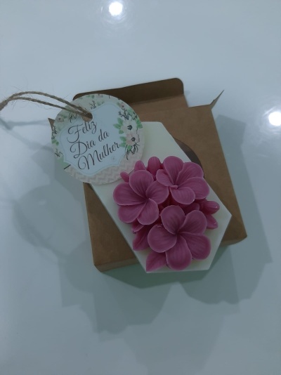Vela decorativa branca com flores rosa e etiqueta Feliz Dia da Mulher