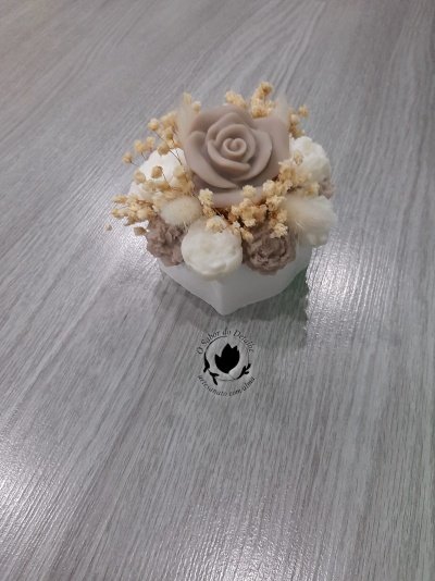 Arranjo decorativo com flores artificiais em vaso branco sobre madeira cinza